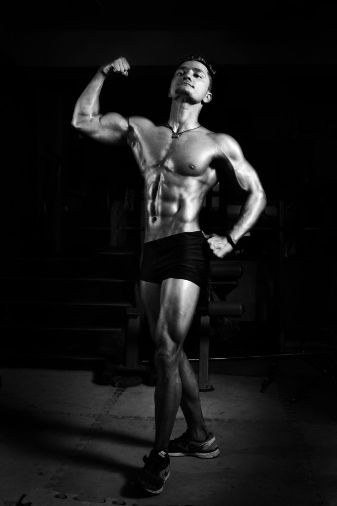 pexels-photo-896061-896061 Powerful black and white image of a male bodybuilder flexing muscles in a gym setting.